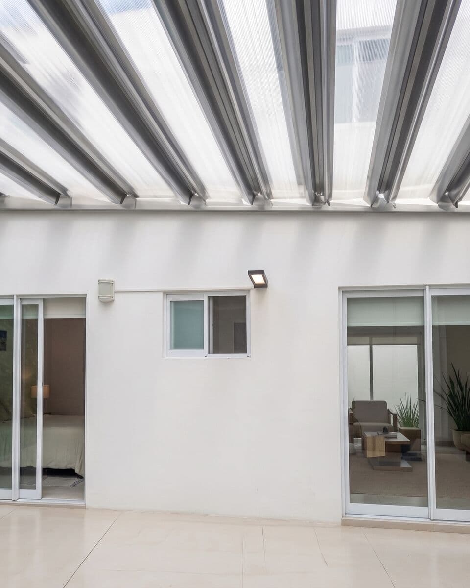 Terraza con pergolado de marimbado en aluminio y policarbonato sobre corredizas de aluminio blanco